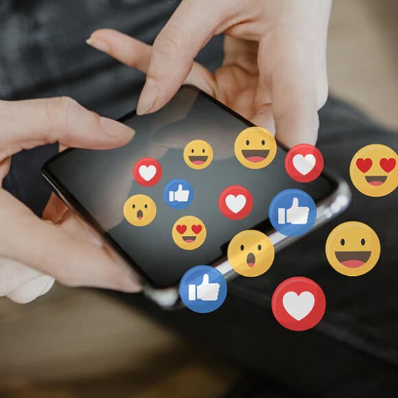 Woman holding a mobile phone with many social media icons on top of it.