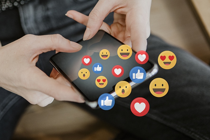 Woman holding a mobile phone with many social media icons on top of it.